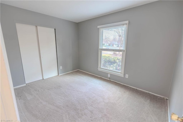 unfurnished bedroom featuring light carpet and a closet