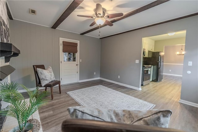 living area with beam ceiling, ceiling fan, and light wood-type flooring