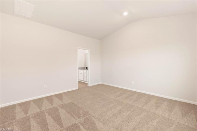 carpeted empty room with vaulted ceiling