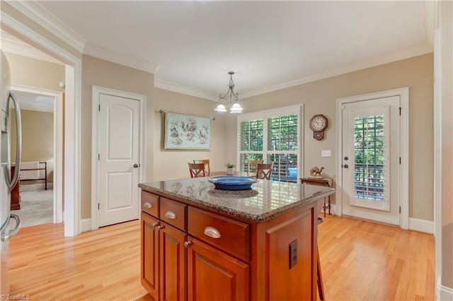 kitchen featuring hanging light fixtures, crown molding, a center island, an inviting chandelier, and light wood-type flooring