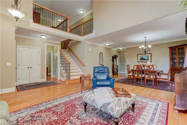 living room with a notable chandelier, ornamental molding, and wood-type flooring