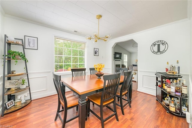 1229 Martin St, Winston-Salem, NC 27103 - dining room with arched walkways, ornamental molding, wood finished floors, a decorative wall, and a wainscoted wall