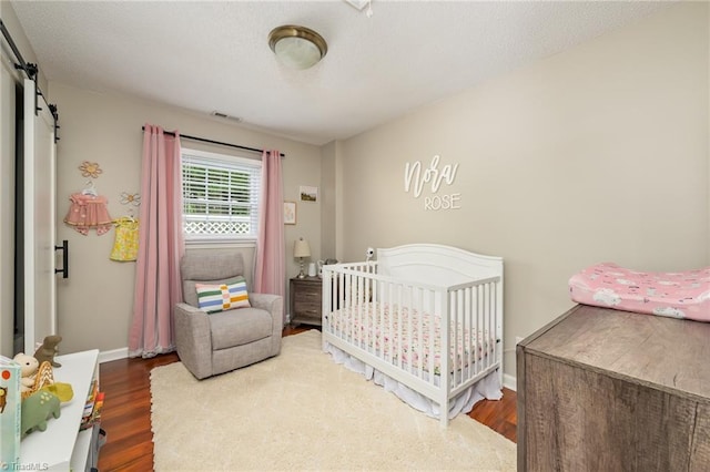 1229 Martin St, Winston-Salem, NC 27103 - bedroom featuring a barn door, wood finished floors, and baseboards