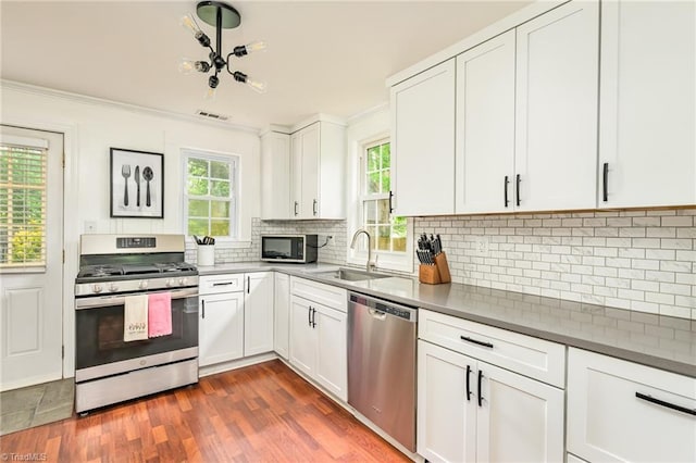 1229 Martin St, Winston-Salem, NC 27103 - kitchen featuring stainless steel appliances, a sink, ornamental molding, decorative backsplash, and white cabinets