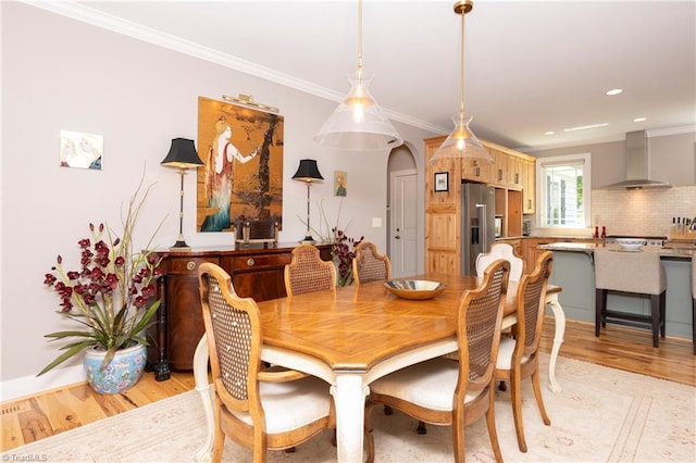 dining space with ornamental molding and light wood-type flooring