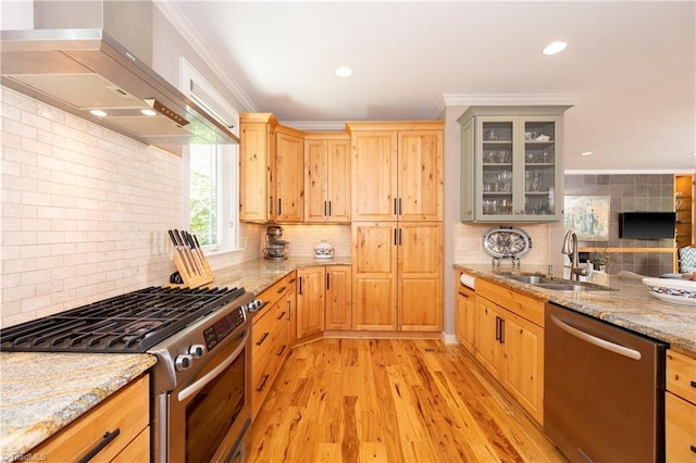 kitchen featuring appliances with stainless steel finishes, sink, ornamental molding, light stone countertops, and wall chimney exhaust hood