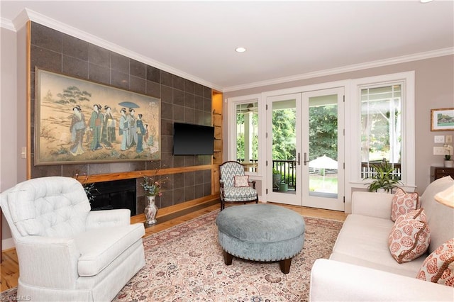 living room featuring crown molding, french doors, a tile fireplace, and hardwood / wood-style flooring