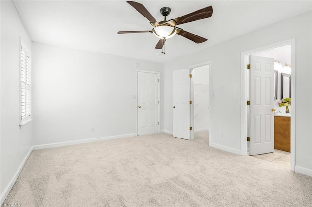 unfurnished bedroom with light carpet, ceiling fan, ensuite bathroom, and a walk in closet