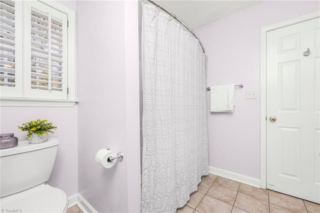 bathroom with tile patterned floors, toilet, a textured ceiling, and curtained shower