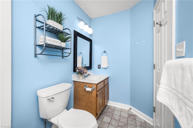 bathroom with a textured ceiling, vanity, toilet, and tile patterned floors