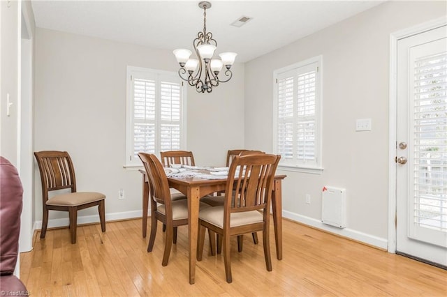 dining area with an inviting chandelier and light hardwood / wood-style flooring