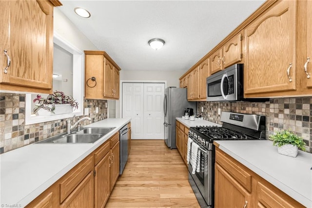 kitchen featuring appliances with stainless steel finishes, sink, light hardwood / wood-style floors, and backsplash