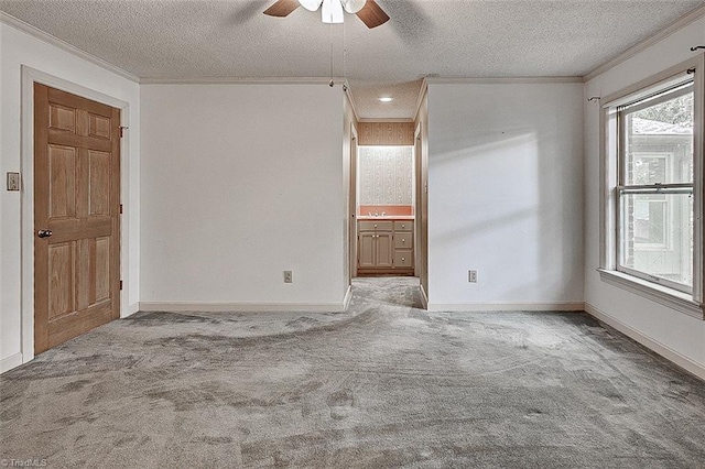 carpeted spare room featuring ceiling fan, a textured ceiling, and crown molding