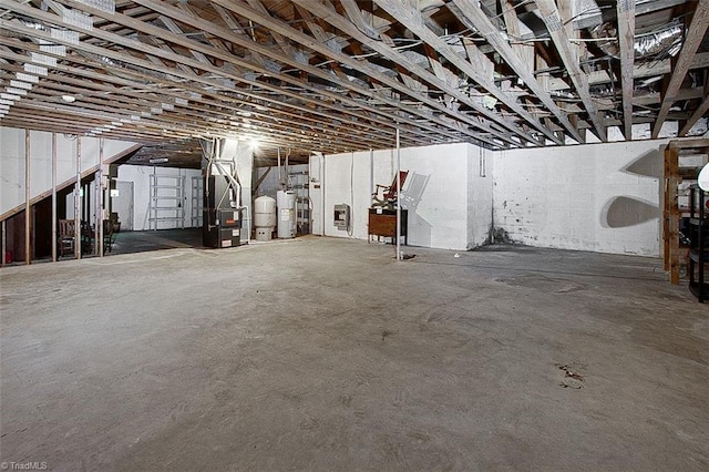 basement featuring electric water heater and heating unit