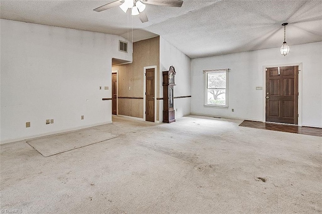 interior space with vaulted ceiling, ceiling fan, carpet floors, and a textured ceiling