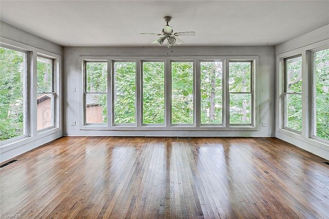 unfurnished sunroom featuring ceiling fan and a wealth of natural light