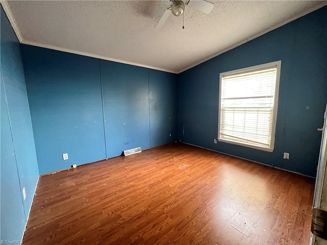 unfurnished room featuring hardwood / wood-style floors, a textured ceiling, and lofted ceiling