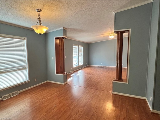 empty room with crown molding, a textured ceiling, and hardwood / wood-style flooring