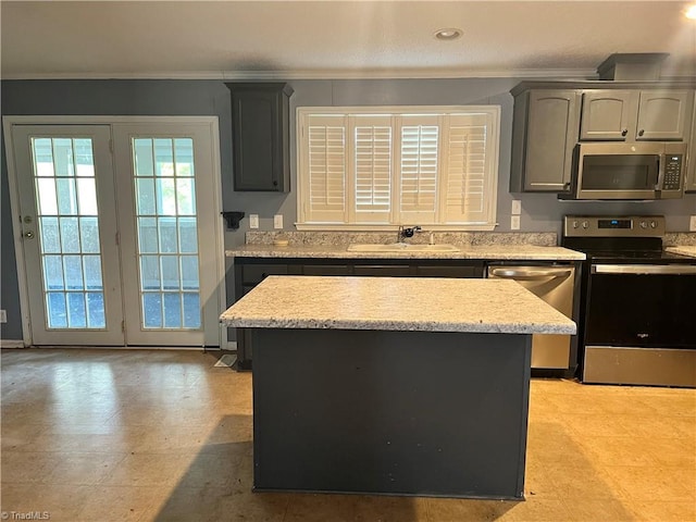 kitchen featuring a kitchen island, sink, ornamental molding, and stainless steel appliances