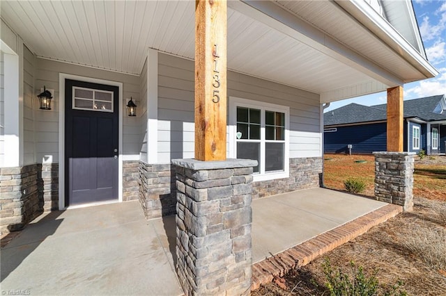 entrance to property featuring stone siding and covered porch