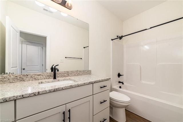 bathroom featuring vanity, wood finished floors, visible vents, shower / tub combination, and toilet