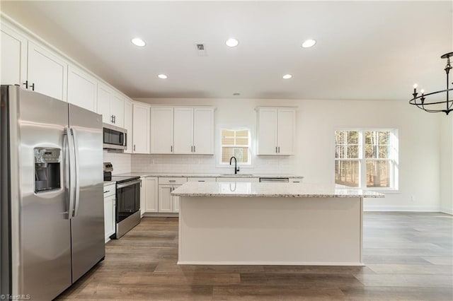 kitchen with decorative backsplash, white cabinetry, appliances with stainless steel finishes, and a kitchen island