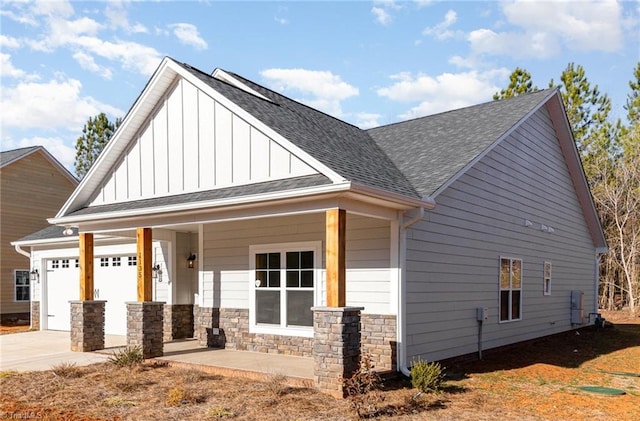view of front of house with board and batten siding, concrete driveway, covered porch, a garage, and stone siding