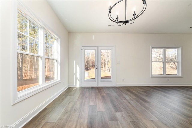unfurnished dining area with a notable chandelier, wood finished floors, and plenty of natural light