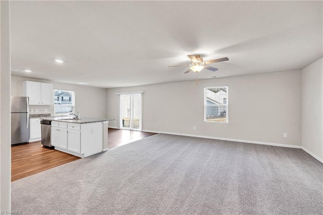 kitchen with appliances with stainless steel finishes, a ceiling fan, carpet, and a sink