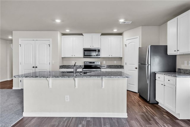 kitchen featuring visible vents, stone countertops, a sink, stainless steel appliances, and white cabinetry