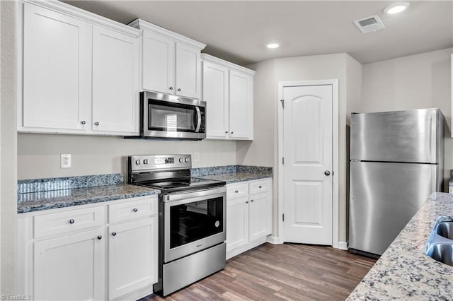 kitchen with dark wood-type flooring, light stone counters, recessed lighting, white cabinets, and stainless steel appliances