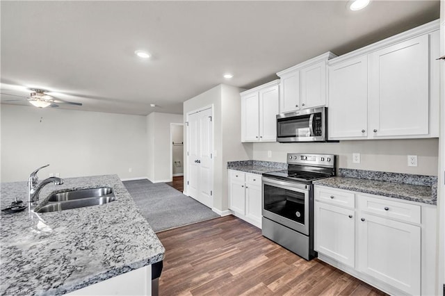 kitchen featuring a sink, wood finished floors, white cabinetry, stainless steel appliances, and ceiling fan