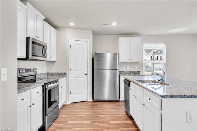 kitchen with visible vents, light wood finished floors, a sink, appliances with stainless steel finishes, and white cabinetry