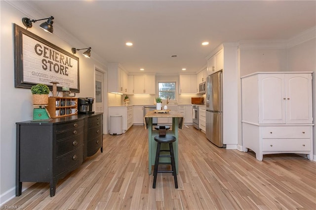 kitchen featuring a center island, light wood-type flooring, white cabinetry, and appliances with stainless steel finishes