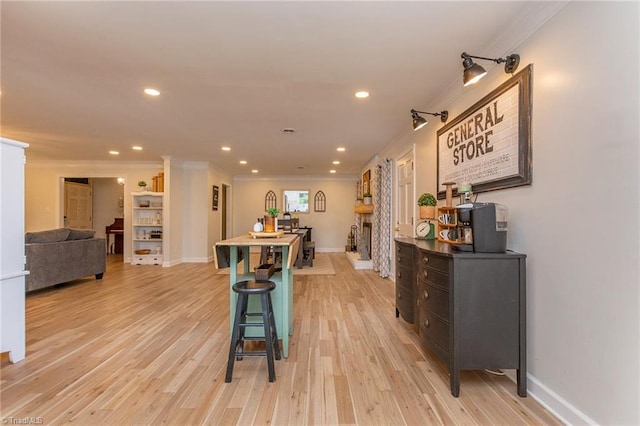 kitchen with a breakfast bar, light hardwood / wood-style flooring, a fireplace, and crown molding