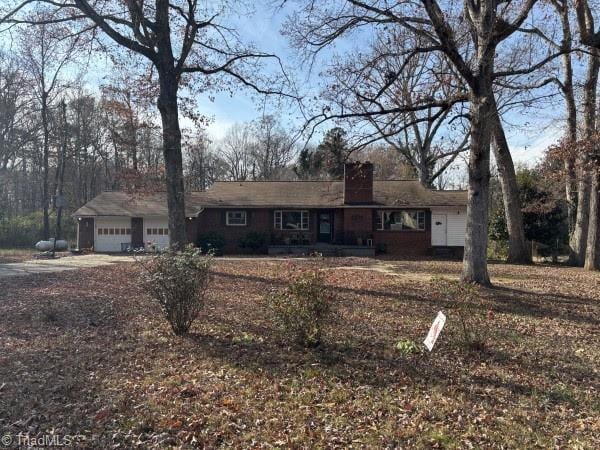 ranch-style home featuring an attached garage and a chimney