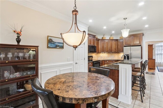 100 Wentworth Dr, Winston-Salem, NC 27107 - kitchen featuring a center island with sink, ornamental molding, black appliances, wainscoting, and tasteful backsplash