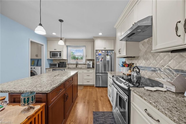1941 Larkhill Dr, Kernersville, NC 27284 - kitchen with wall chimney range hood, stainless steel appliances, washer / clothes dryer, backsplash, and light wood-type flooring