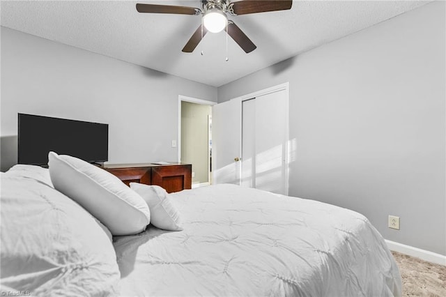 carpeted bedroom with ceiling fan, a textured ceiling, and a closet