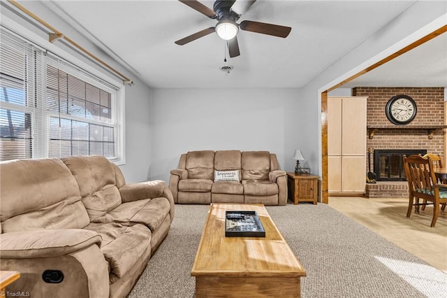 living room featuring light carpet, ceiling fan, and a brick fireplace