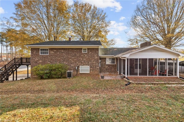 rear view of house featuring a sunroom, a lawn, and central AC