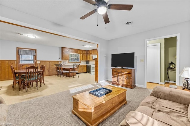 carpeted living room featuring ceiling fan and wooden walls