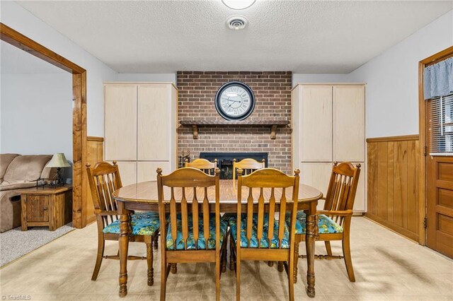 dining area featuring wood walls, a fireplace, and a textured ceiling