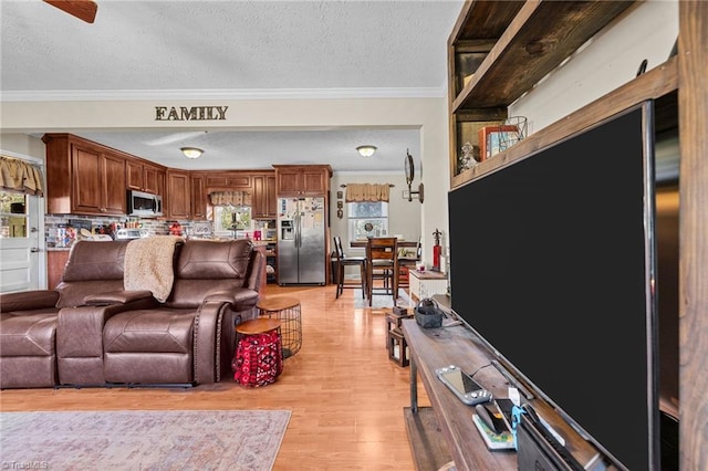 living room with ceiling fan, light hardwood / wood-style floors, a textured ceiling, and ornamental molding