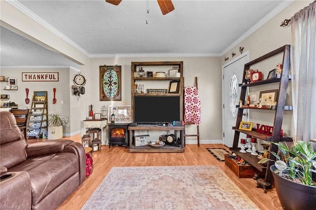 living room with a textured ceiling, hardwood / wood-style flooring, ceiling fan, and crown molding