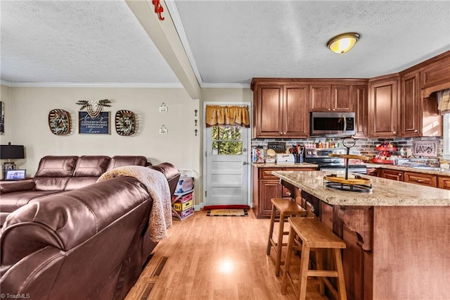 kitchen featuring a center island, a textured ceiling, a breakfast bar, appliances with stainless steel finishes, and ornamental molding