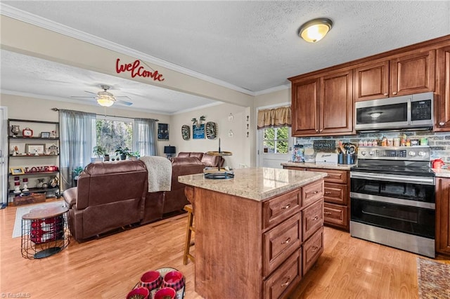 kitchen featuring crown molding, light hardwood / wood-style flooring, a textured ceiling, a kitchen island, and stainless steel appliances