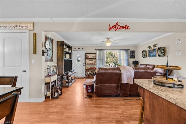 living room featuring a textured ceiling, light hardwood / wood-style flooring, ceiling fan, and crown molding