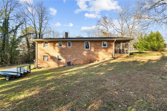 rear view of property with a sunroom, a yard, and central AC