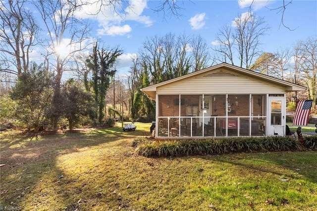 rear view of house with a sunroom and a lawn